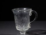a glass cup sitting on a table with a black background