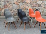 trois chaises de couleurs différentes, placées côte à côte devant un mur de pierre