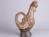 a brown vase with a bird on it on a white surface