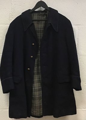 un manteau noir accroché au mur, à côté d'un mur de briques blanches