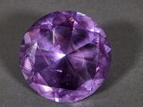 a close up of a purple gemstone on a black surface