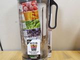 a blender sitting on a wooden table with various fruits and vegetables in it