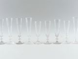 six clear wine glasses lined up in a row on a white surface