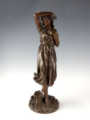 une statue antique en bronze représentant une femme tenant un panier sur la tête