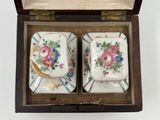 two small dishes in a wooden box on a white surface