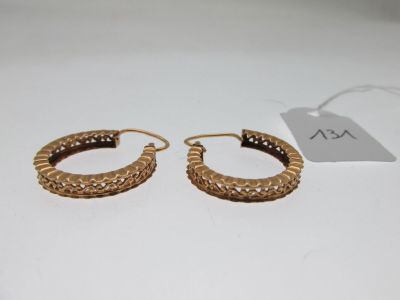 a pair of gold hoop earrings on a white surface