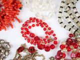 many different colored beads and necklaces on a white surface