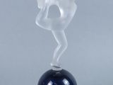 a glass figurine of a woman on top of a ball
