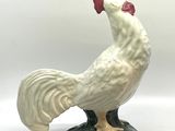 une figurine représentant un coq blanc sur un socle vert