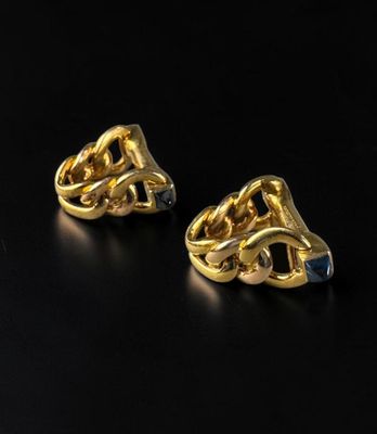 a pair of gold earrings on a black surface