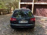 a black car parked in front of a house in the woods