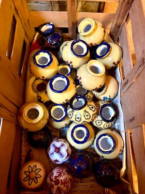 de nombreux vases de toutes sortes dans une caisse en bois posée par terre