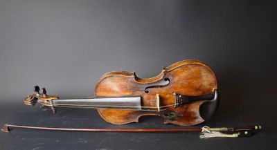 an old violin sits on a black surface next to a bow