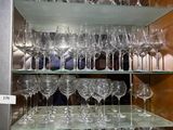 many wine glasses on a shelf in a glass case