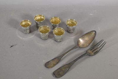une cuillère, une fourchette et des tasses posées sur une table