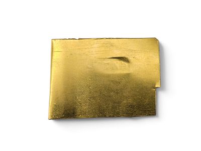 an image of a piece of gold metal on a white surface