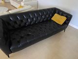un canapé en cuir noir avec un coussin jaune dans un salon