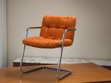 une chaise orange posée sur une table en bois