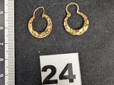 deux paires de boucles d'oreilles créoles en or posées sur une surface noire, à côté d'une règle