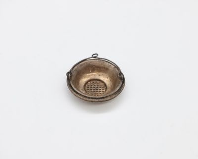 a small metal bowl with a handle on a white surface
