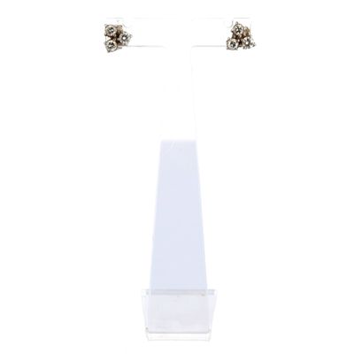 une paire de boucles d'oreilles à clous en argent et diamants noirs, posées sur un socle blanc