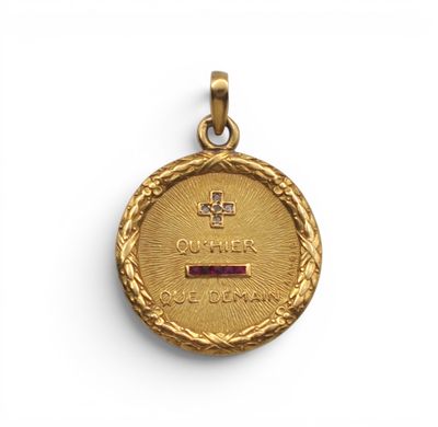 une médaille d'or ornée d'une croix et d'une pierre rouge au centre