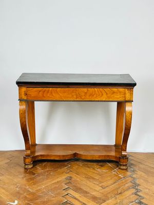 une photo d'une table en bois avec un plateau noir posée sur un parquet