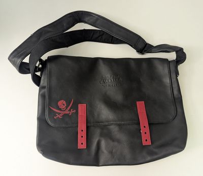 sac messager en cuir noir avec des sangles rouges et un motif représentant une tête de mort et des os croisés