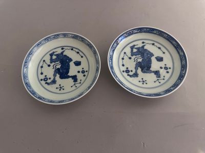 pair of blue and white plates with figures on them on a table