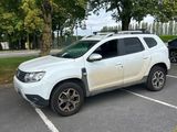 La voiture blanche est garée sur le parking, près des arbres.