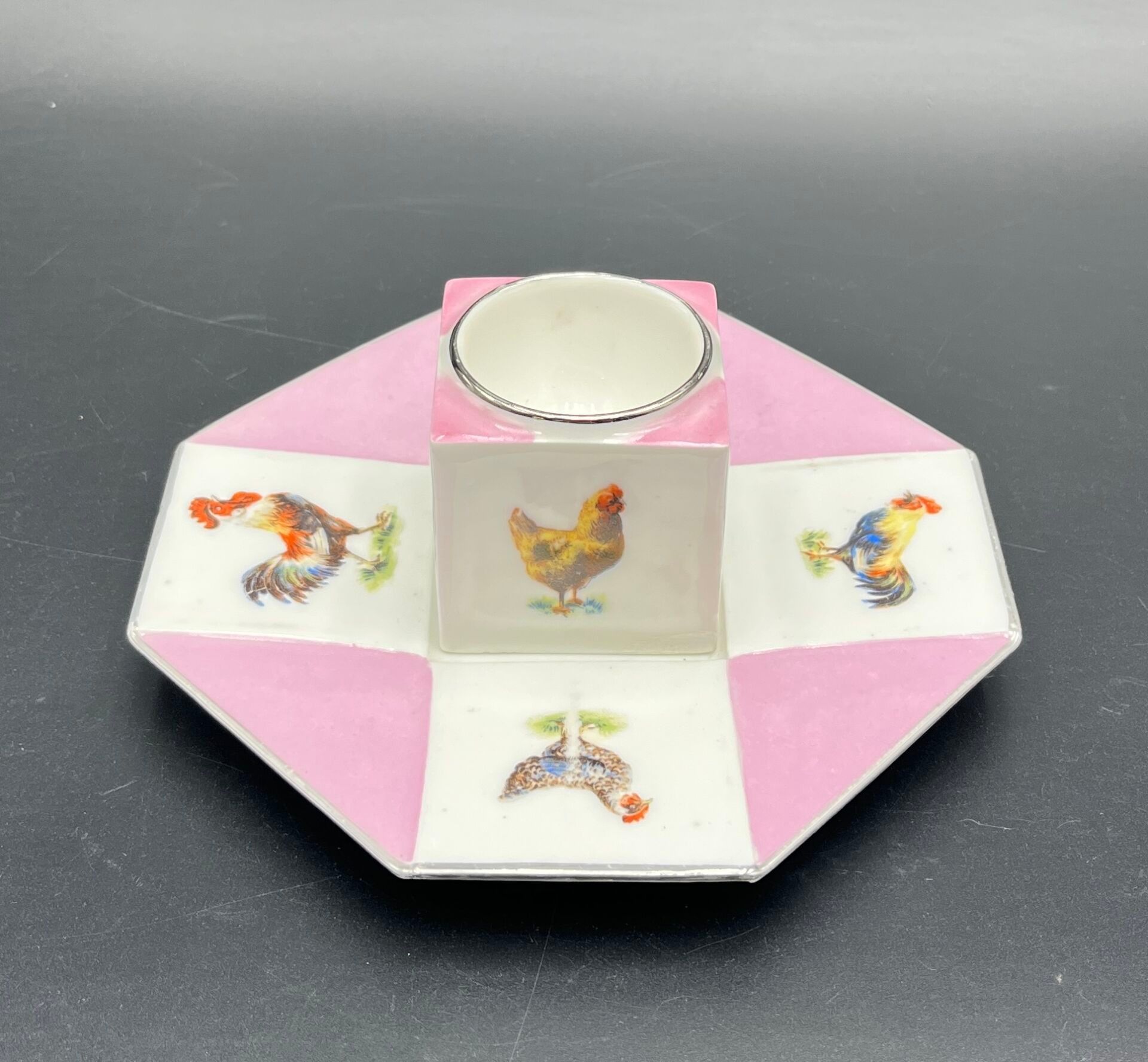 FRANCE - PRODUX Un coquetier cube et sa coupelle à pans coupés à fond blanc et rose pâle et décor polychrome de poule...