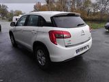 the rear end of a white car parked in a parking lot