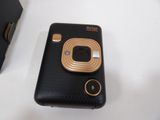 a black and gold camera sitting on a table next to a cell phone