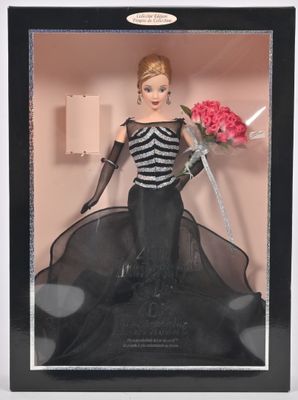 une poupée Barbie vêtue d'une robe noire et blanche, tenant un bouquet de fleurs