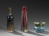 trois vases en verre de couleurs différentes posés les uns à côté des autres sur une table
