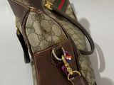 brown and green guccissi bag on white background with brown strap