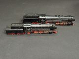 two black and red trains sitting on a gray surface