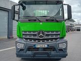 un camion vert qui roule dans la rue devant un immeuble