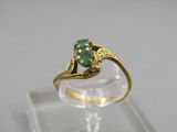 gros plan d'une bague en or avec une pierre verte