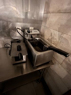 two deep fryers sitting on a table in a kitchen