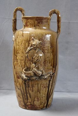 a brown vase with a bird on it sitting on a branch