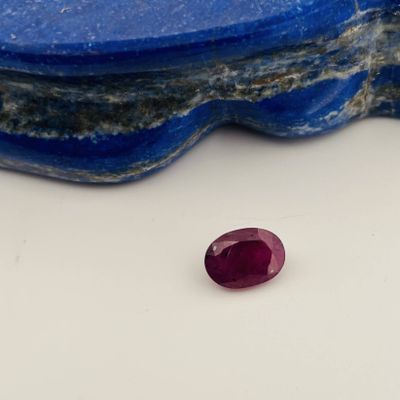 a close up of a red ruby stone sitting on top of a blue stone