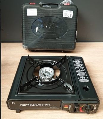 un réchaud à gaz portable posé sur une table à côté d'une valise