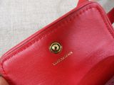 someone is holding a small red purse with a gold button