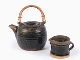 une petite théière et une tasse posées sur une surface blanche