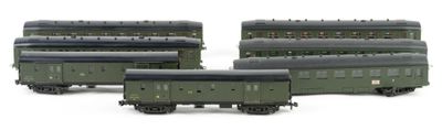 three green train cars sitting next to each other on a white surface