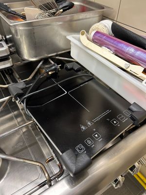 une cuisinière avec une casserole posée dessus, dans une cuisine