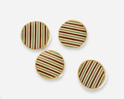 trois petits boutons rayés sont posés sur une surface blanche