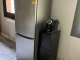 a silver refrigerator and a black refrigerator freezer in a room