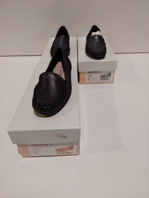 une paire de chaussures noires posée sur une boîte, elle-même posée sur une surface blanche